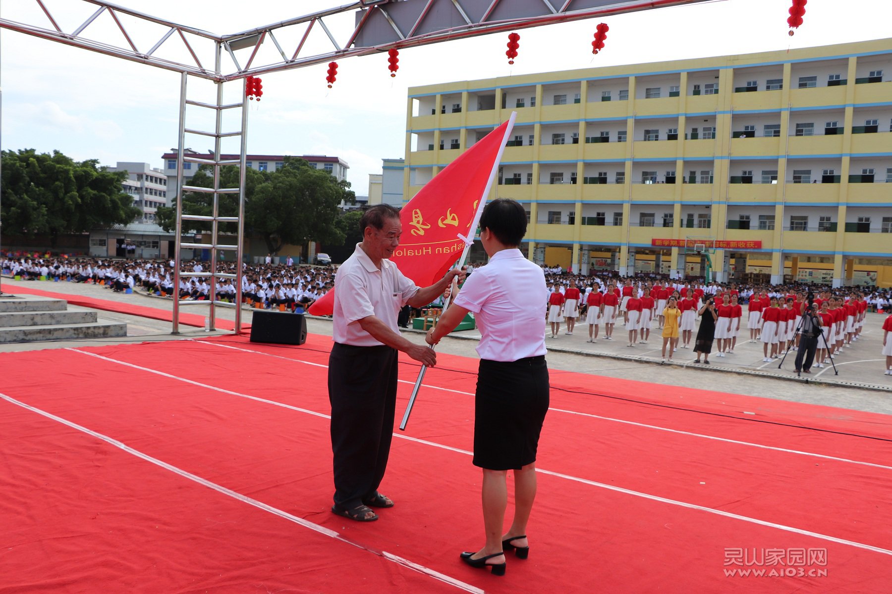 现任校长从老校长手中接过校旗，寓意着“师魂”的传承